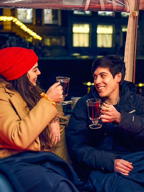 Couple enjoying mulled wine on Amsterdam Light Festival cruise.