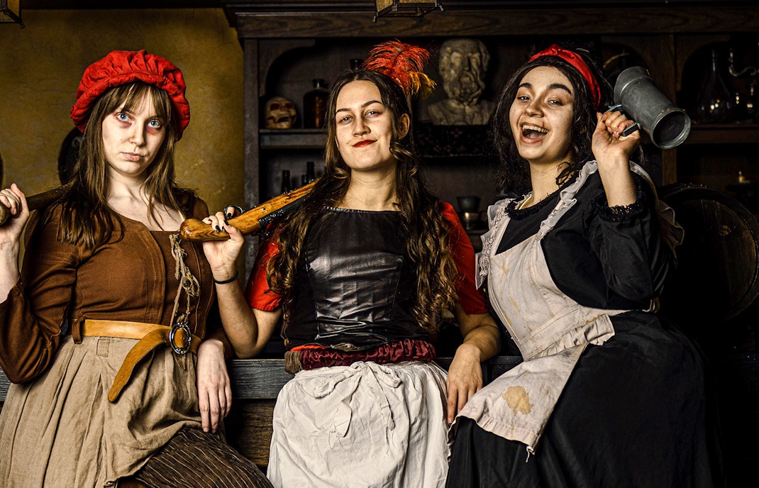 Guests in historical costumes at the Amsterdam Dungeon experience.