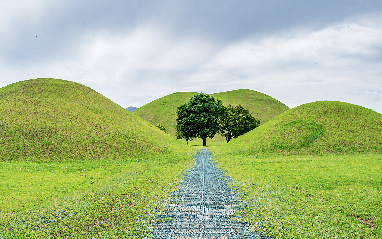 Pathway through grassy burial mounds in Gyeongju, South Korea, UNESCO World Heritage site.
