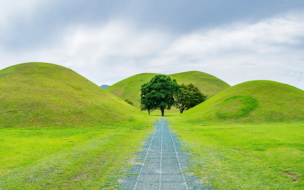 Pathway through grassy burial mounds in Gyeongju, South Korea, UNESCO World Heritage site.