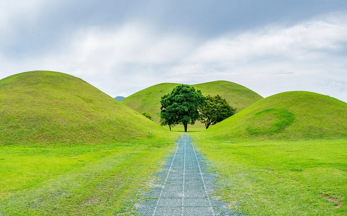 Pathway through grassy burial mounds in Gyeongju, South Korea, UNESCO World Heritage site.