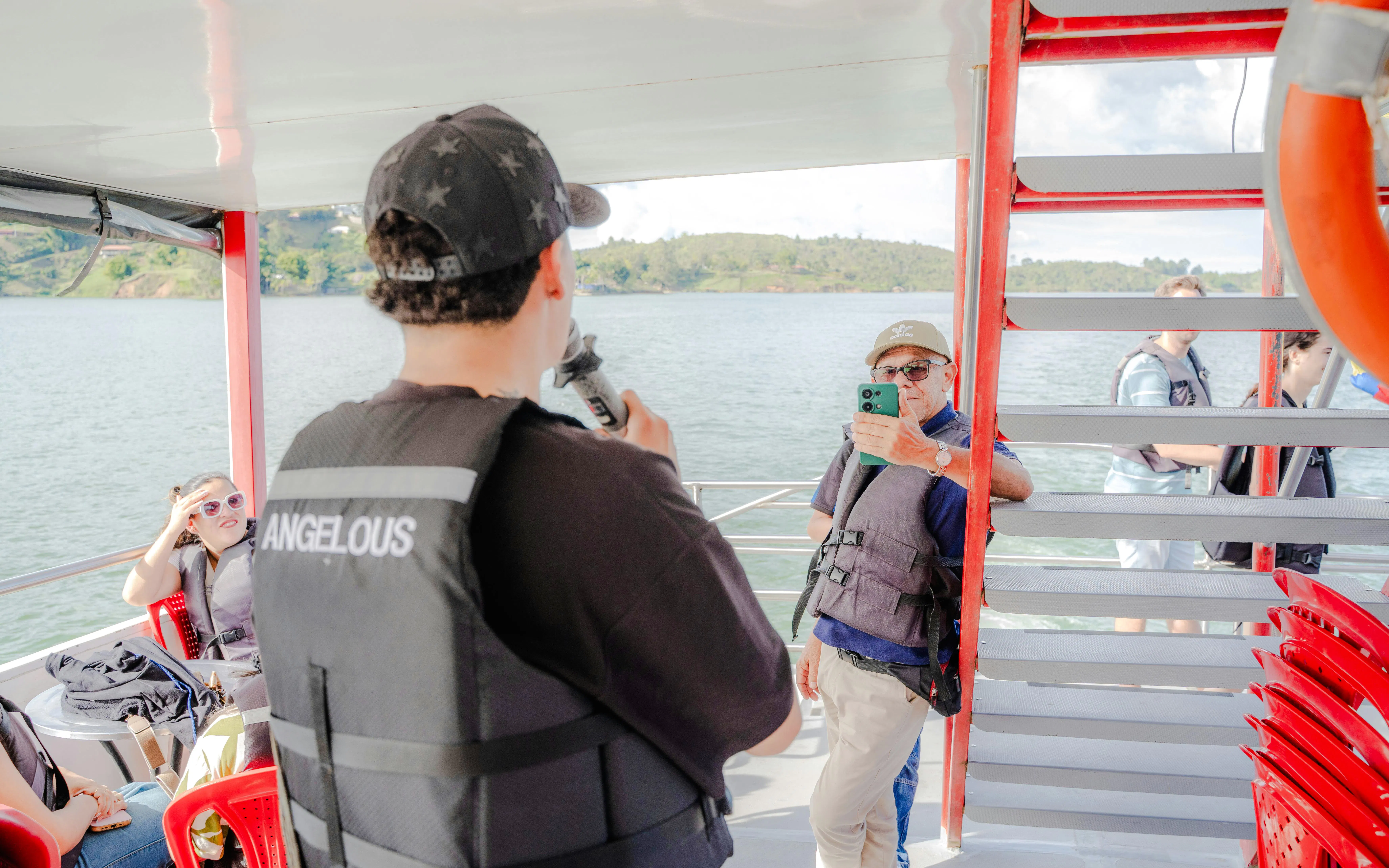 Boat ride on Guatapé reservoir with tourists enjoying the view and taking photos.