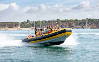 Boat tour on the Arade River with passengers enjoying the ride, Monchique Mountain in background.