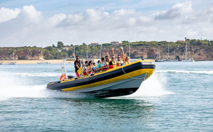 Boat tour on the Arade River with passengers enjoying the ride, Monchique Mountain in background.