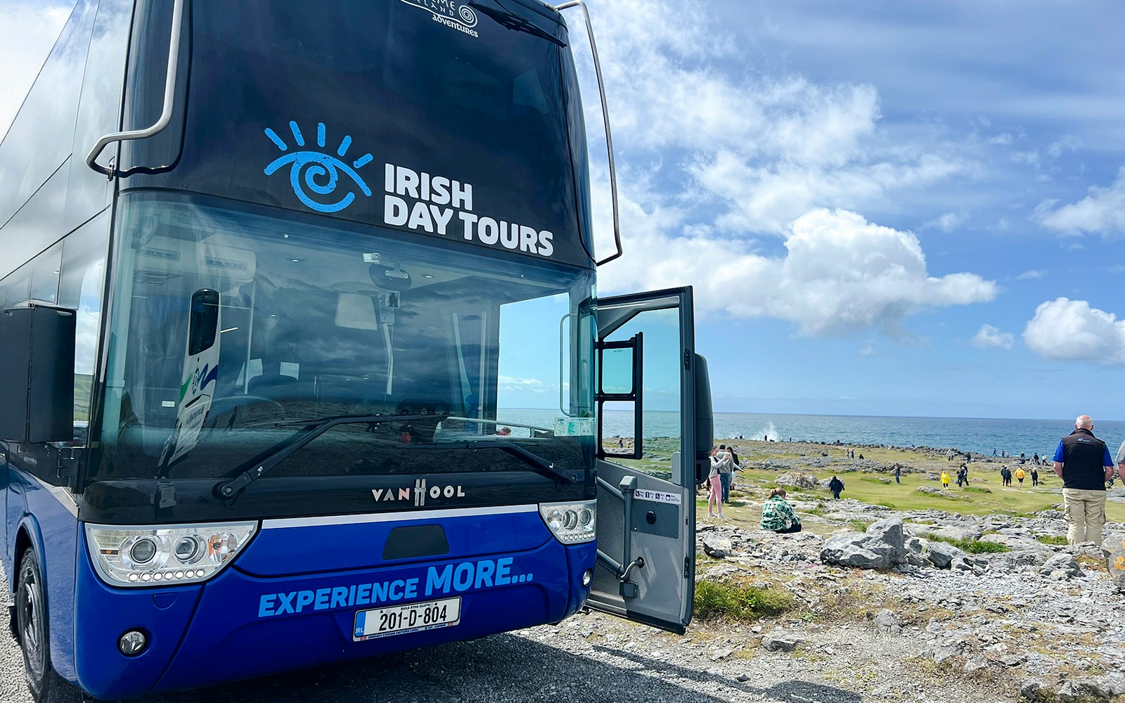 Bus for Irish Day Tours parked near Cliffs of Moher with ocean view.