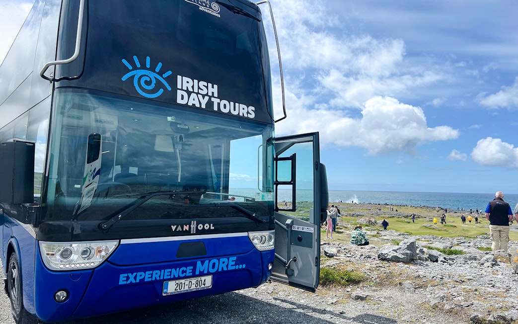 Bus for Irish Day Tours parked near Cliffs of Moher with ocean view.