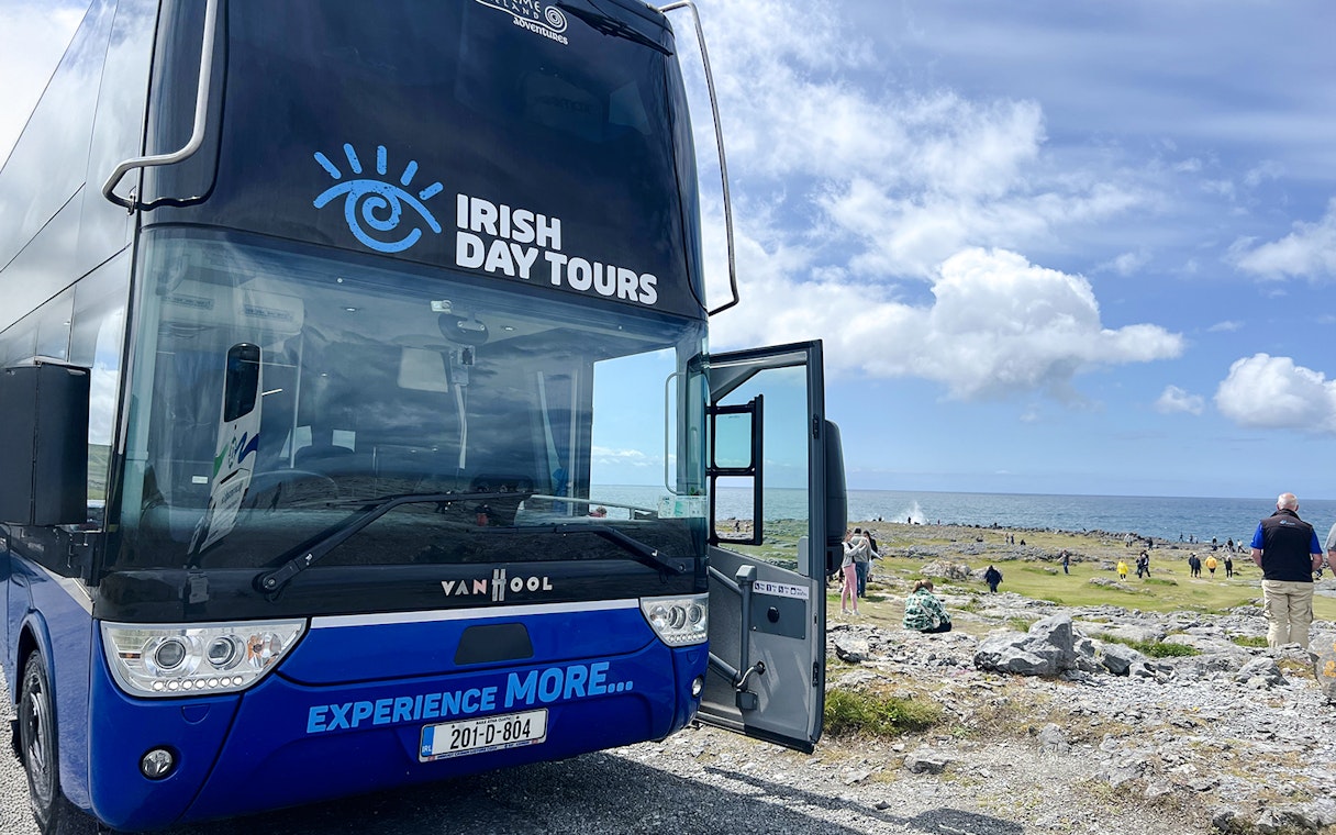 Bus for Irish Day Tours parked near Cliffs of Moher with ocean view.
