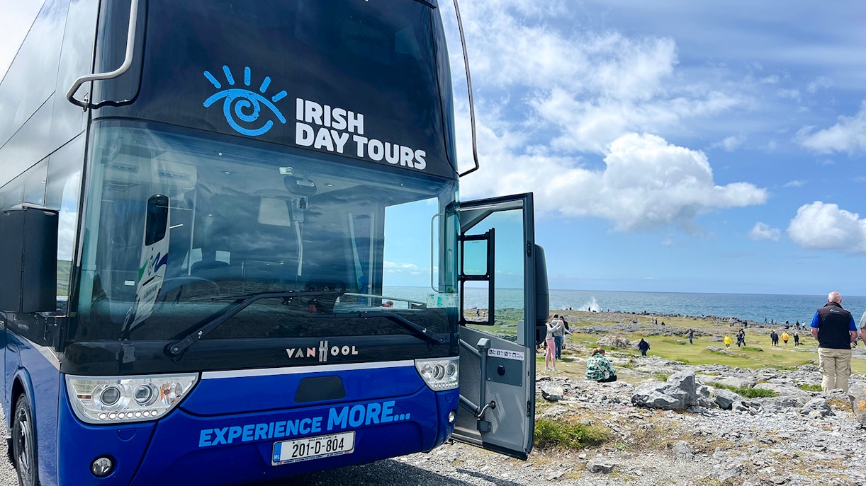 Bus for Irish Day Tours parked near Cliffs of Moher with ocean view.