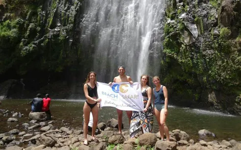 Group at Materuni Waterfall holding a tour banner, Arusha, Tanzania.