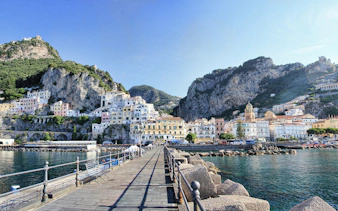 Amalfi Coast view with colorful cliffside buildings and a waterfront promenade.