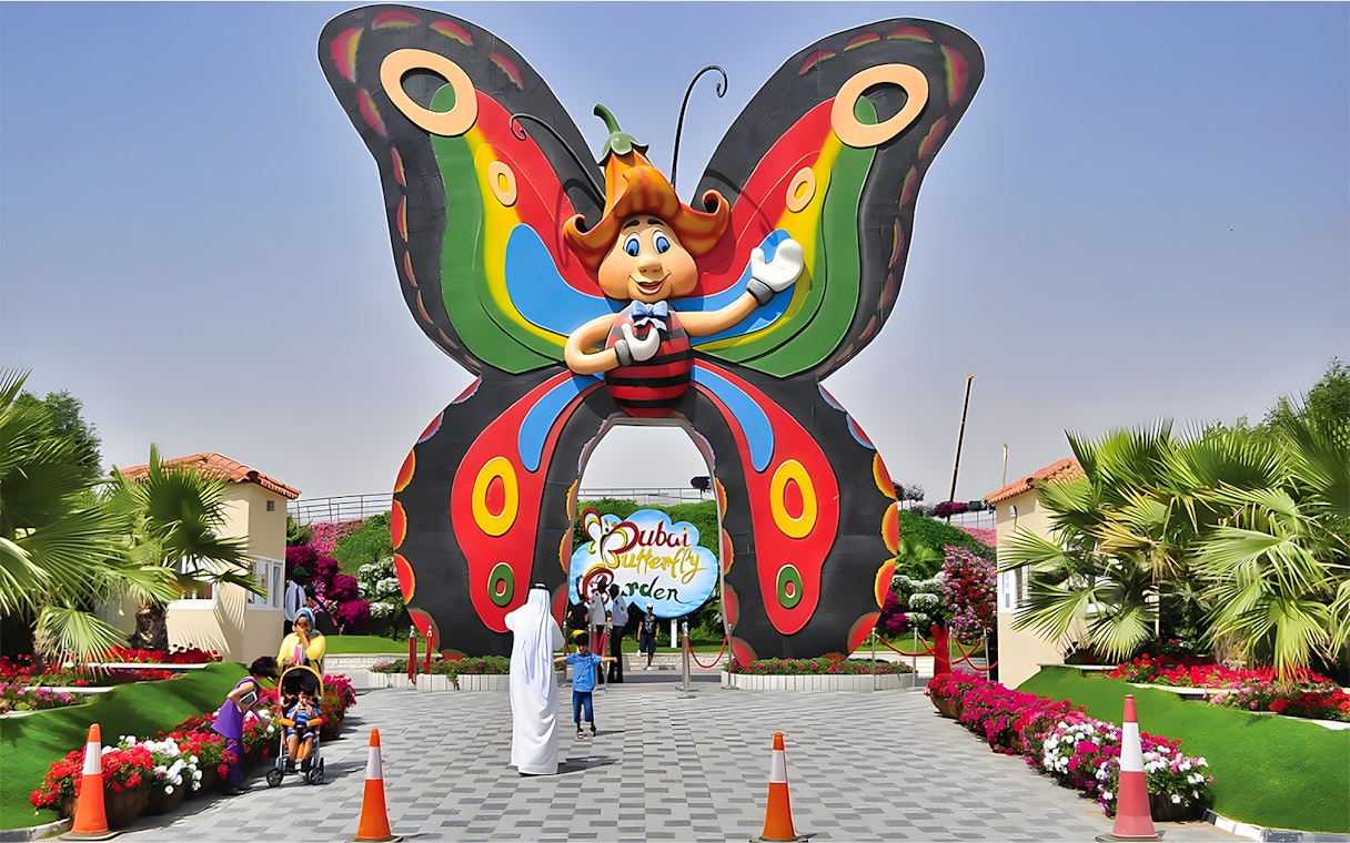 Entrance to Dubai Butterfly Garden with colorful butterfly arch and visitors.