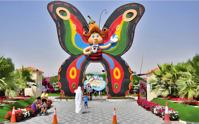 Entrance to Dubai Butterfly Garden with colorful butterfly arch and visitors.