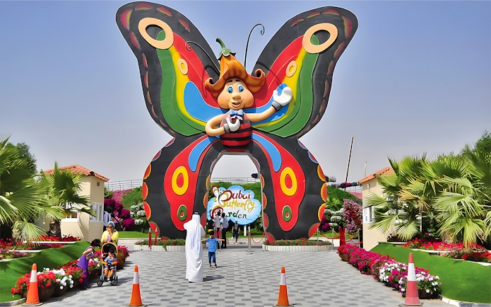 Entrance to Dubai Butterfly Garden with colorful butterfly arch and visitors.