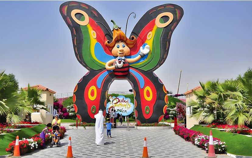 Entrance to Dubai Butterfly Garden with colorful butterfly arch and visitors.