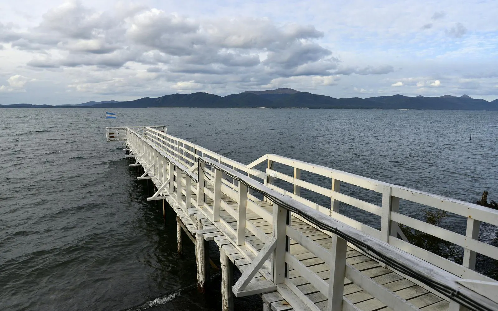 Wooden pier extending into Lago Fagnano with mountains in Ushuaia, Argentina.