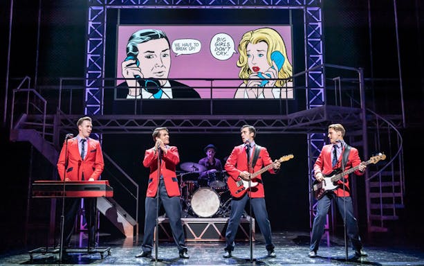 Performers in red jackets on stage during a Jersey Boys musical scene.