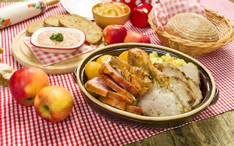 Traditional Czech meal with roast meats, bread, and apples on a checkered tablecloth in Prague.