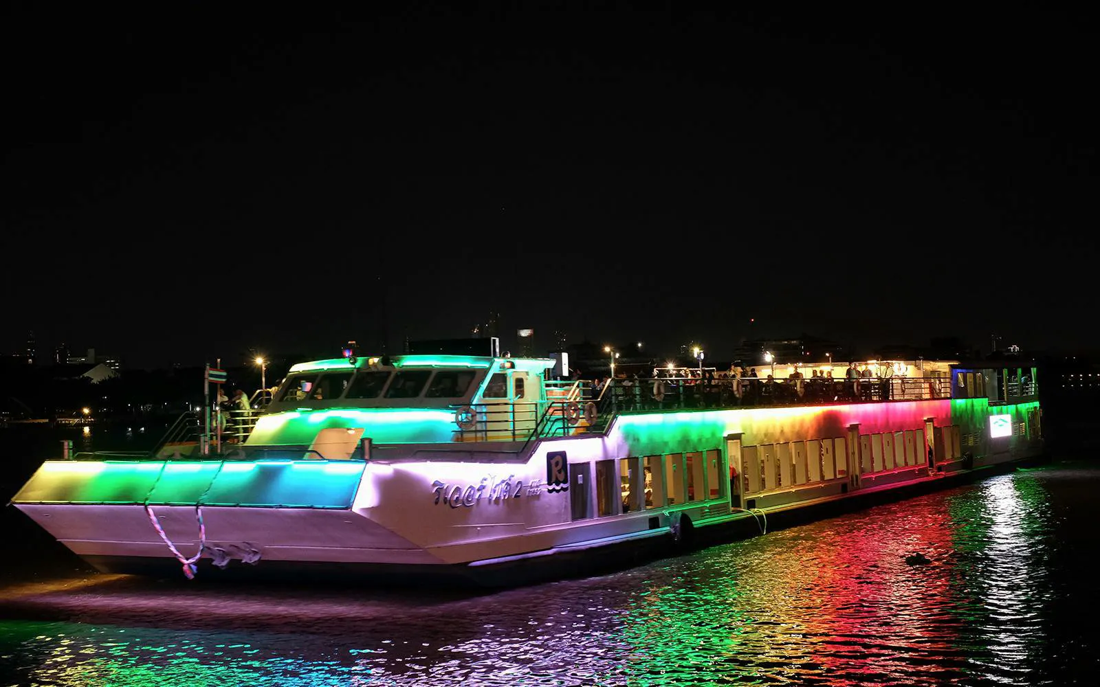 Riverside Kinlen Cruise boat illuminated at night on the Chao Phraya River in Bangkok.