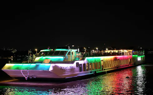 Riverside Kinlen Cruise boat illuminated at night on the Chao Phraya River in Bangkok.
