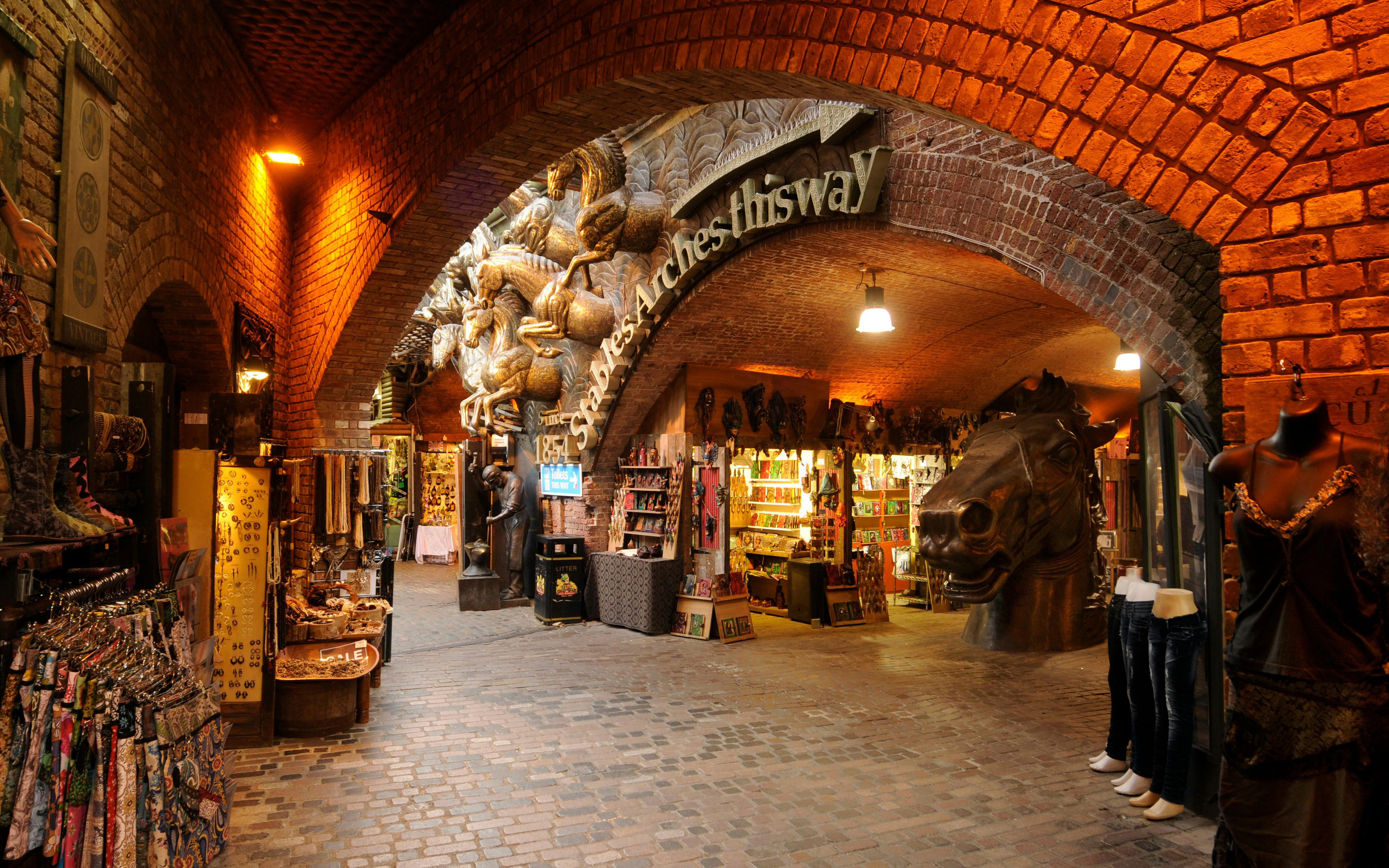 Stables Market in London with shops under brick arches and horse sculptures.