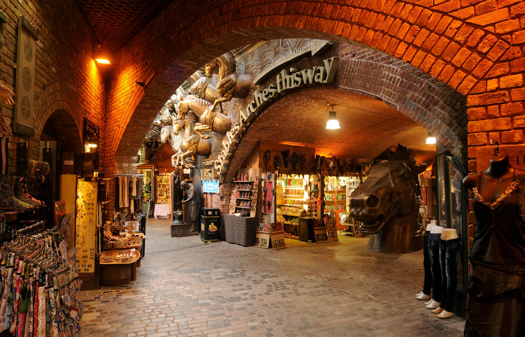 Stables Market in London with shops under brick arches and horse sculptures.