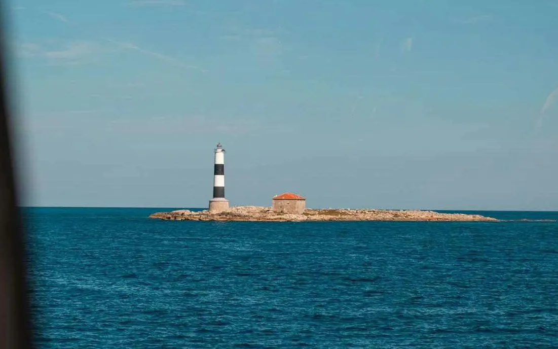 Den Pou Lighthouse on Illa des Porcs island surrounded by blue sea.