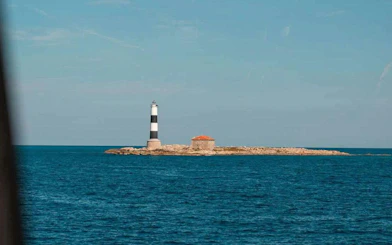 Den Pou Lighthouse on Illa des Porcs island surrounded by blue sea.