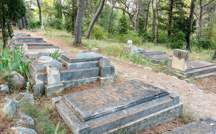 Old Jewish Cemetery in Split, Croatia with historic stone graves surrounded by trees.