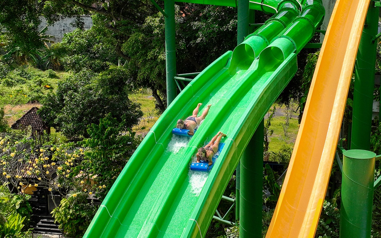 Two girls sliding down Twin Racers waterslide at Waterbom Bali.