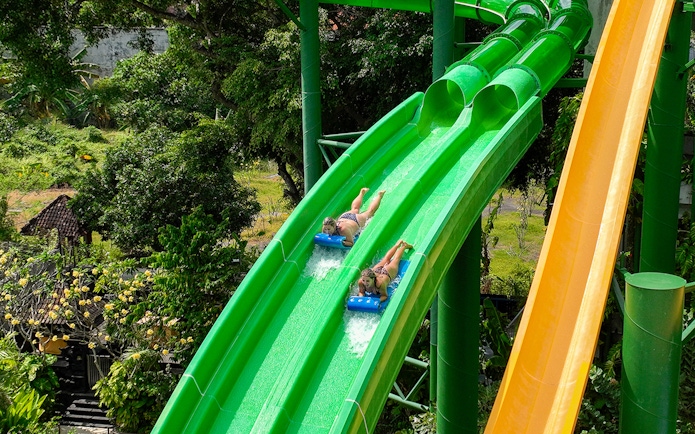 Two girls sliding down Twin Racers waterslide at Waterbom Bali.
