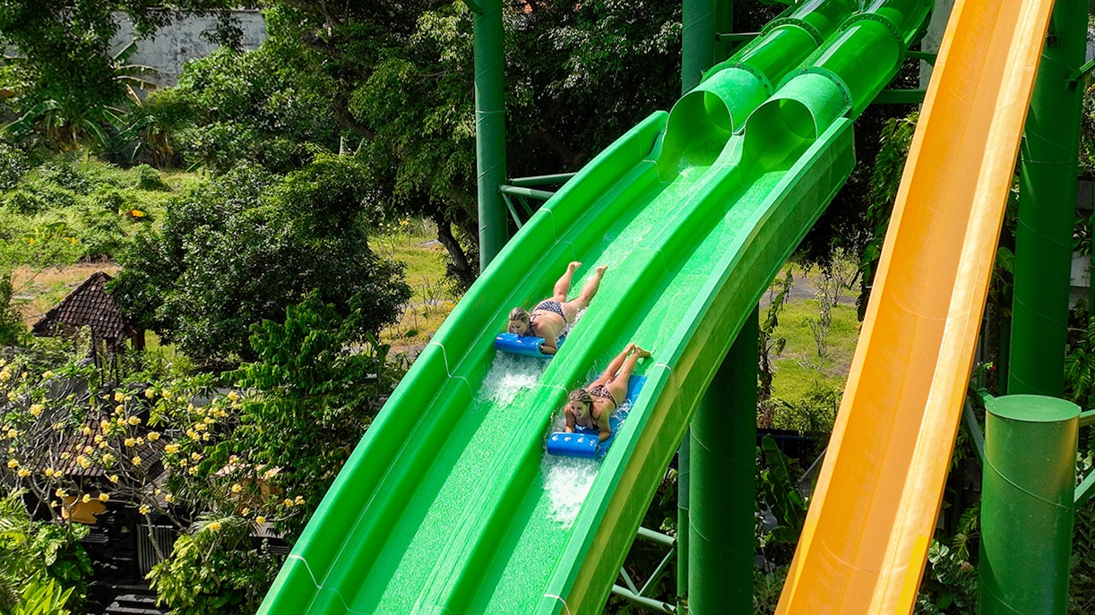 Two girls sliding down Twin Racers waterslide at Waterbom Bali water park, Indonesia.