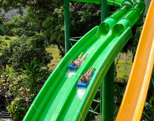 Two girls sliding down Twin Racers waterslide at Waterbom Bali water park, Indonesia.