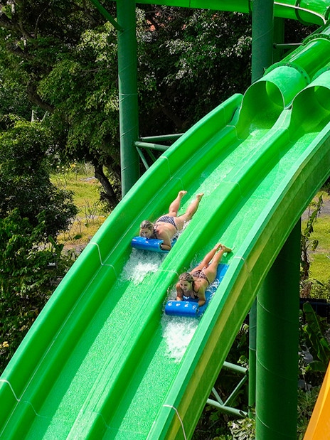 Two girls sliding down Twin Racers waterslide at Waterbom Bali.