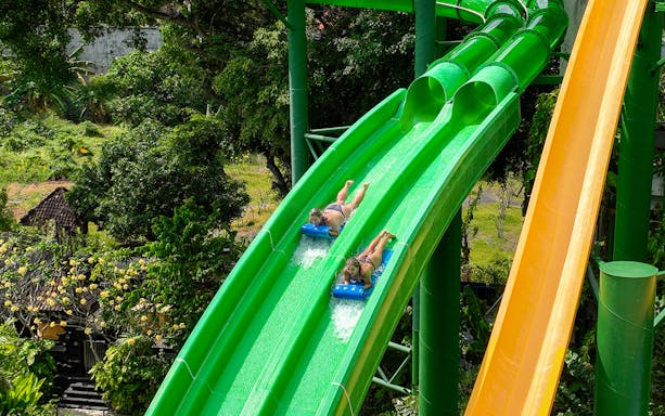 Two girls sliding down Twin Racers waterslide at Waterbom Bali.