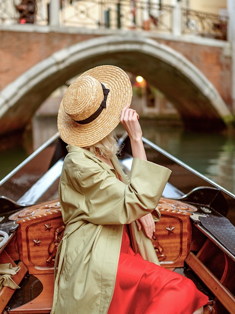 Tourist on gondola ride under bridge in Venice canal.