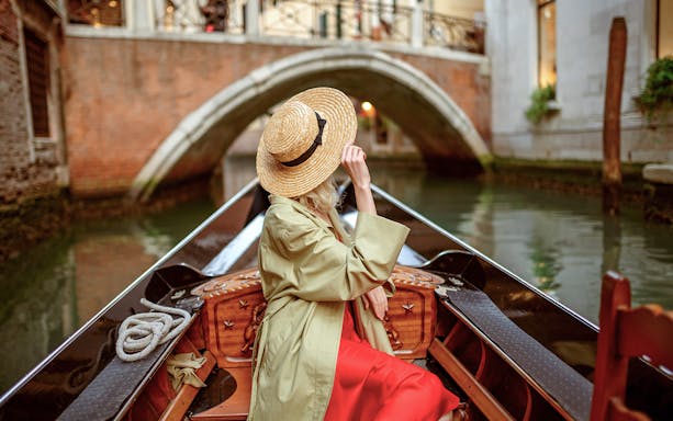 Tourist on gondola ride under bridge in Venice canal.