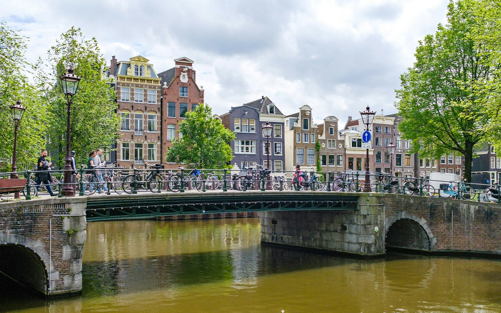 Bridge over Herengracht canal in Amsterdam with bicycles and historic buildings.