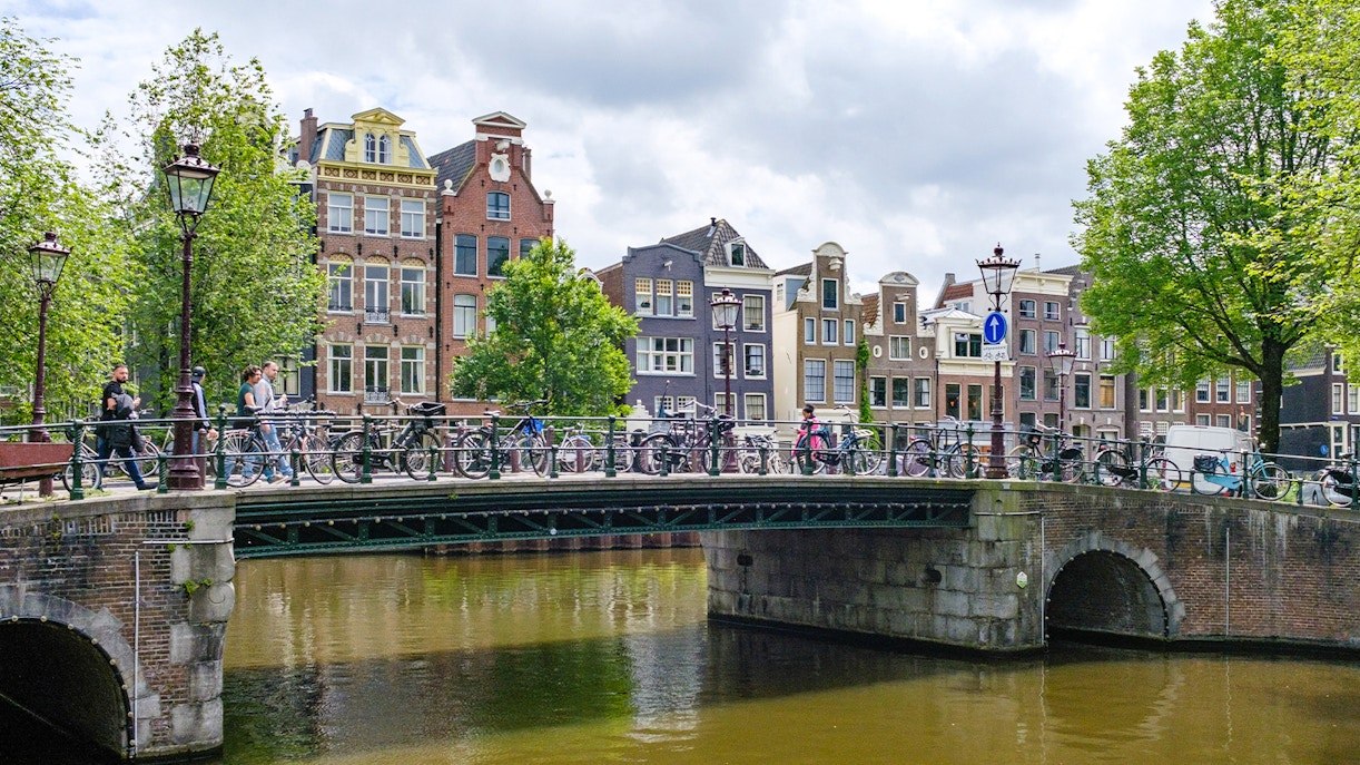 Bridge over Herengracht canal in Amsterdam with bicycles and historic buildings.