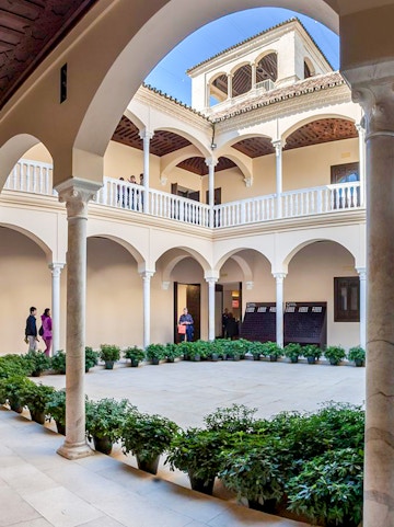 Courtyard of the Picasso Museum in Malaga with arches and potted plants.