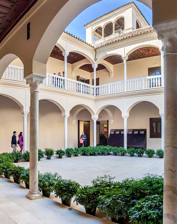 Courtyard of the Picasso Museum in Malaga with arches and potted plants.