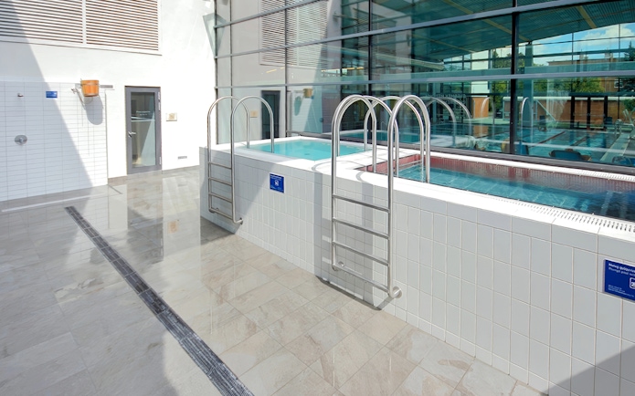 Indoor pools at Paskal Thermal Bath, Budapest with ladders and glass windows.