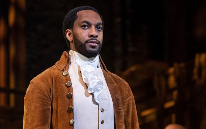 Actor in period costume performing in the musical "Hamilton" on stage.