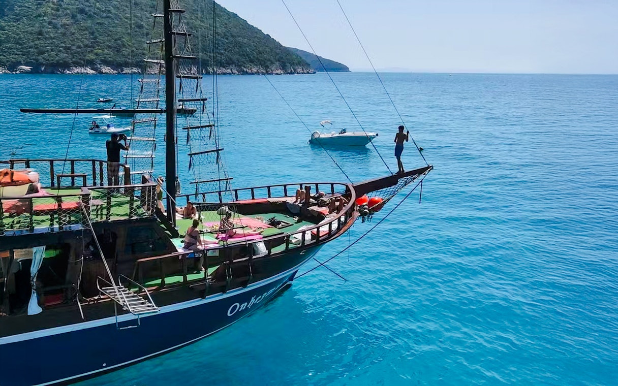 Pirate ship sailing near Saranda with people enjoying the deck and clear blue sea.
