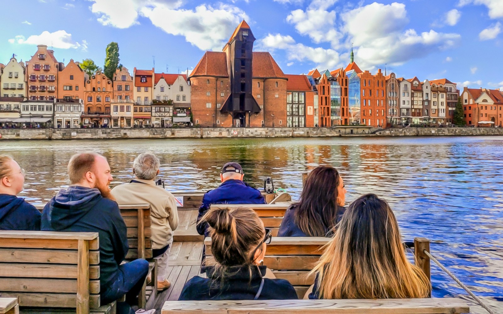 Guests enjoying a 1-hour cruise on a historical Galar boat with a view of Gdańsk waterfront buildings.