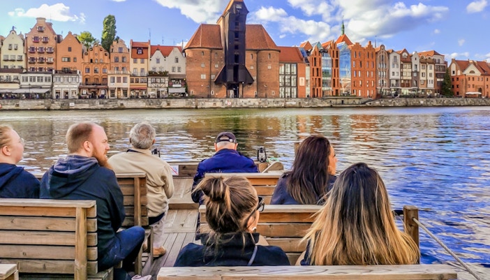 Guests enjoying a 1-hour cruise on a historical Galar boat with a view of Gdańsk waterfront buildings.
