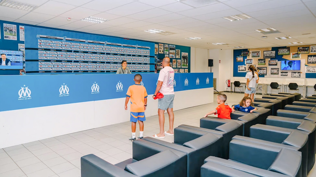 Press room at Velodrome Stadium tour with visitors exploring the space.