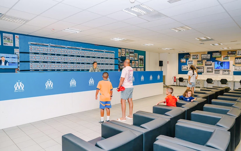 Press room at Velodrome Stadium tour with visitors exploring the space.