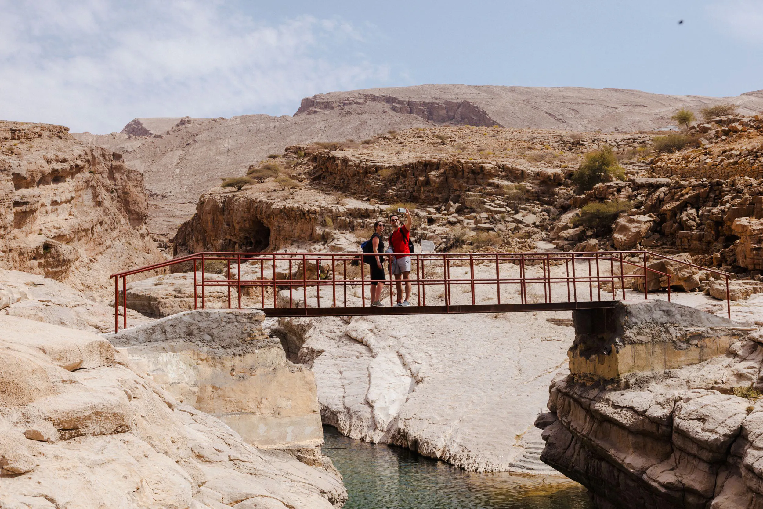 Tourists on a bridge in Wadi Bani Khalid, Oman, during the Wahiba Desert guided tour.