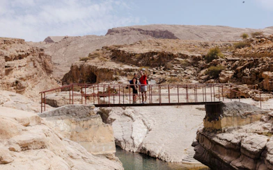 Tourists on a bridge in Wadi Bani Khalid, Oman, during the Wahiba Desert guided tour.