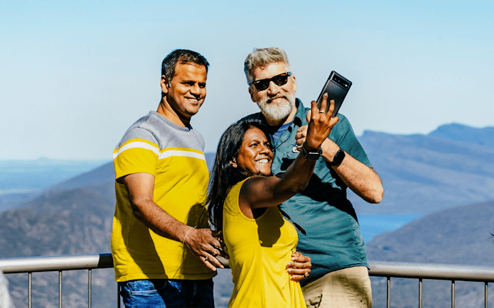 Guests taking a selfie at Boroka Lookout with mountain views in the background.